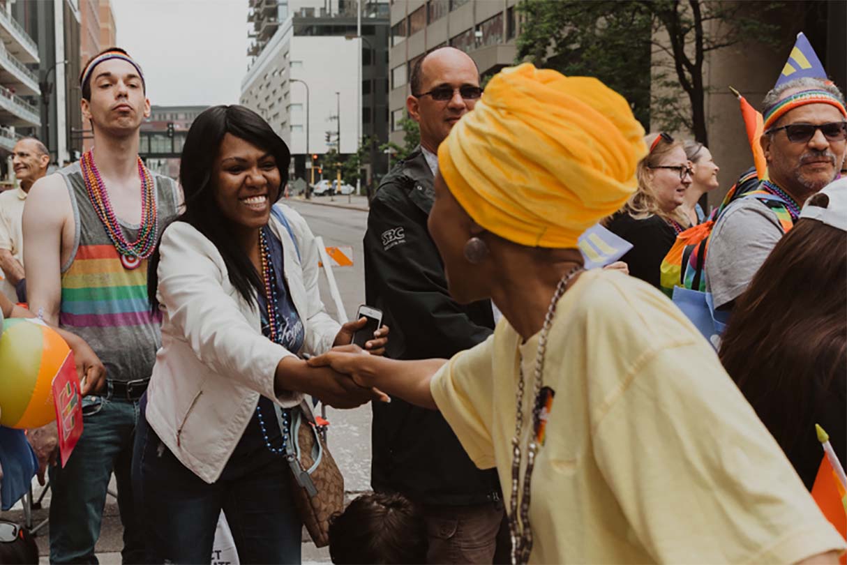 Ilhan in the street shaking hands with a woman